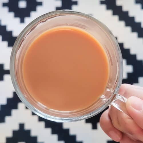 hand holding a hong kong style milk tea in the air