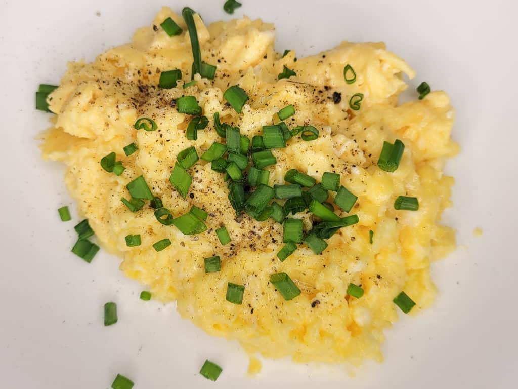 A plate of scrambled eggs with a topping of chives