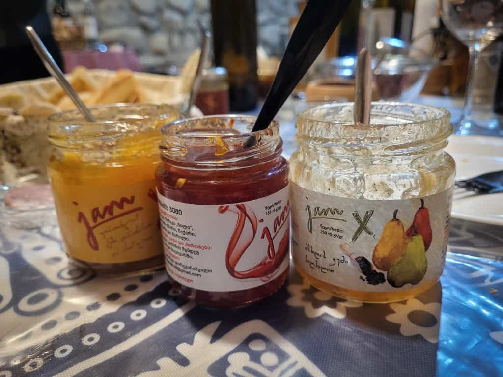 Three different jars side by side of various types of jams on a table