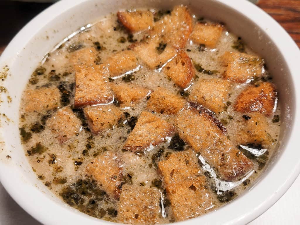 Garlic soup in a white bowl with croutons and cheese