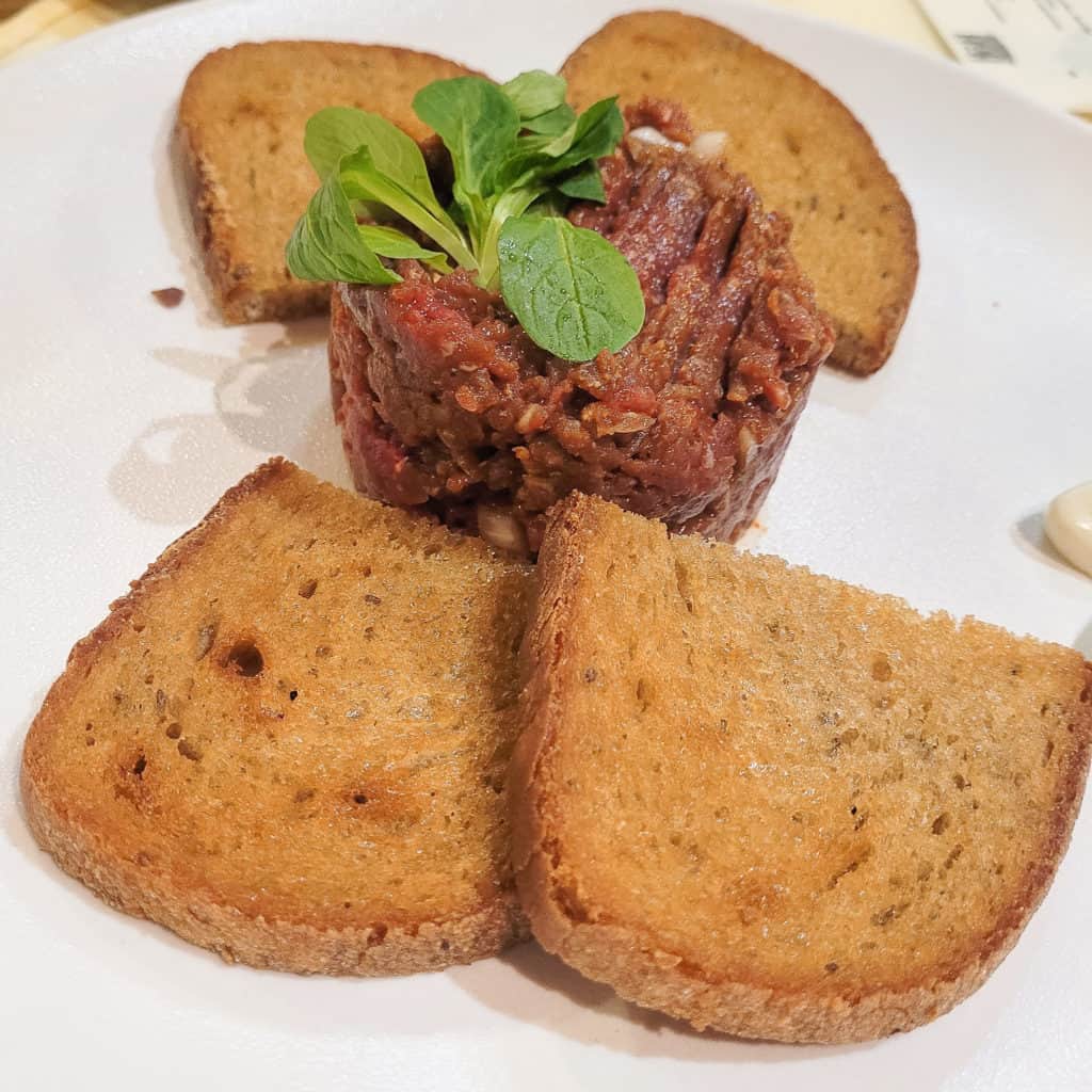 A plate of beef tartare with slices to toasted bread at Bredovský Dvůr .