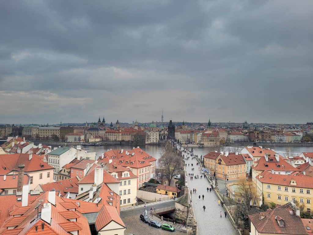 People walking on Charles Bridge surrounded by buildings on a cloudy day 