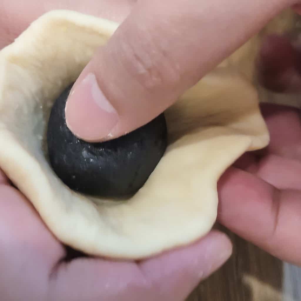 Closeup action shot of wrapping the black sesame seed bun