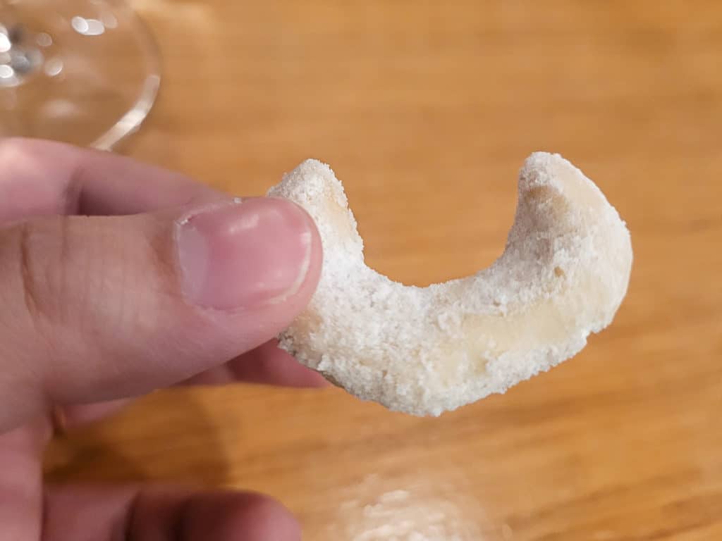 A hand holding a cookie shaped like a crescent moon