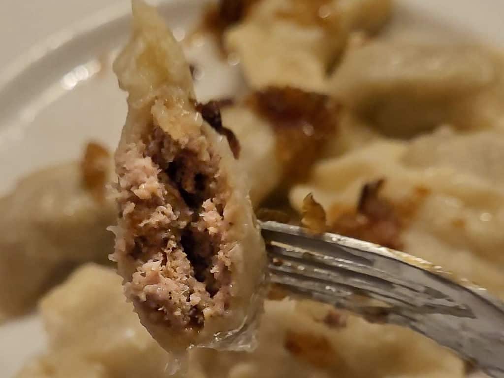 A cross section view of a bitten pierogi filled with duck meat