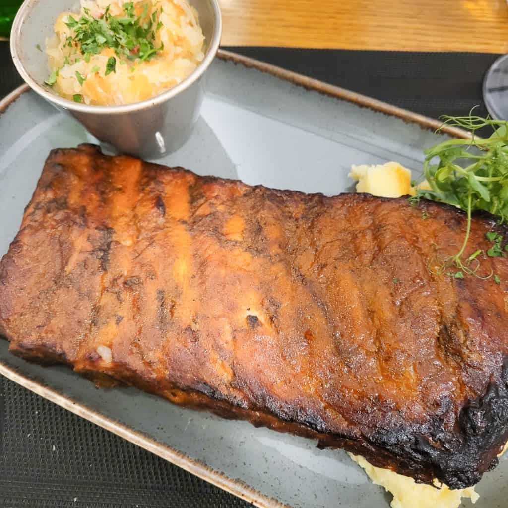 A rack of ribs at on a plate next to cabbage salad