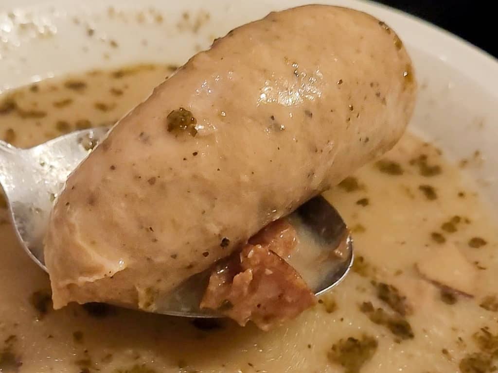 A closeup on a white sausage in a sour rye soup bowl