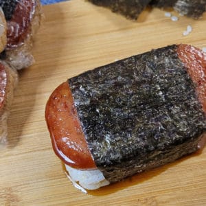 Overhead shot of spam musubi next to some wrapped musubis