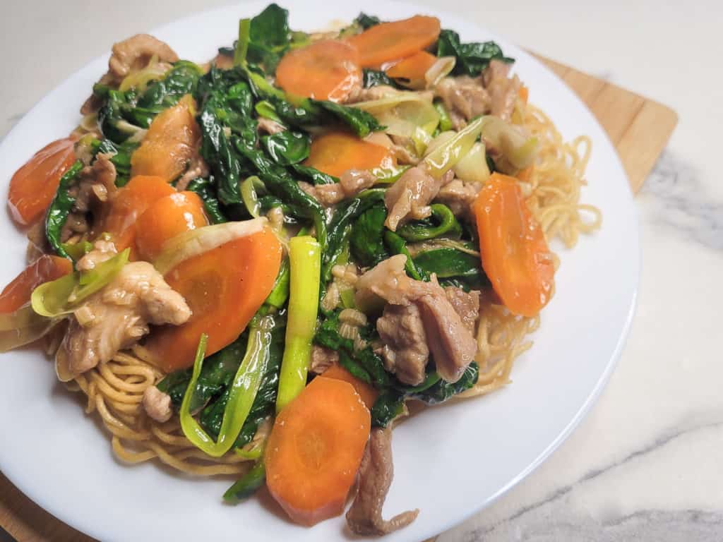 Closeup of crispy noodles with vegetable and meat topping on a cutting board