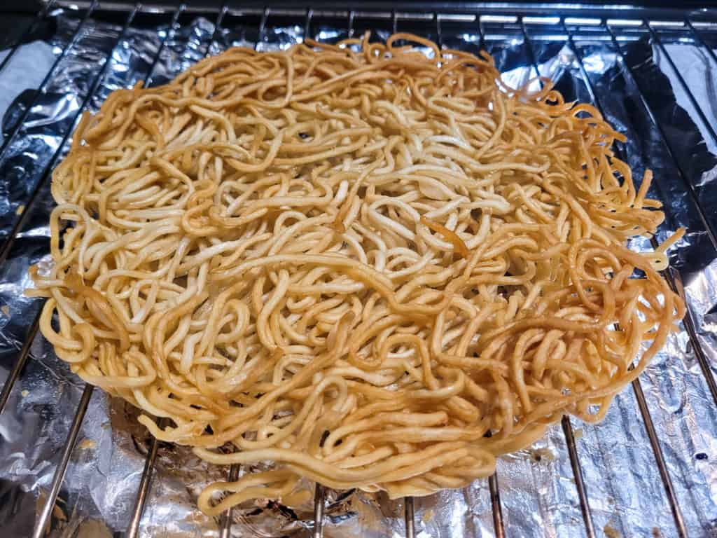 Fried noodles on a wire rack on top of aluminum lined baking sheet