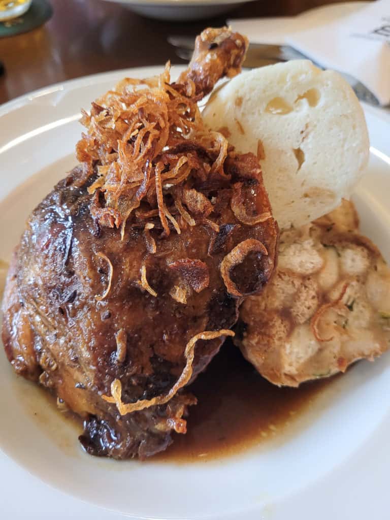 A leg of roasted duck next to bread dumplings