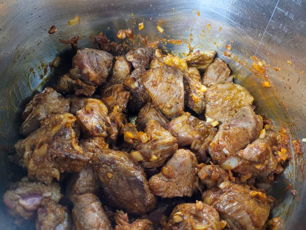 Mix browned beef with tomato paste and garlic and onions