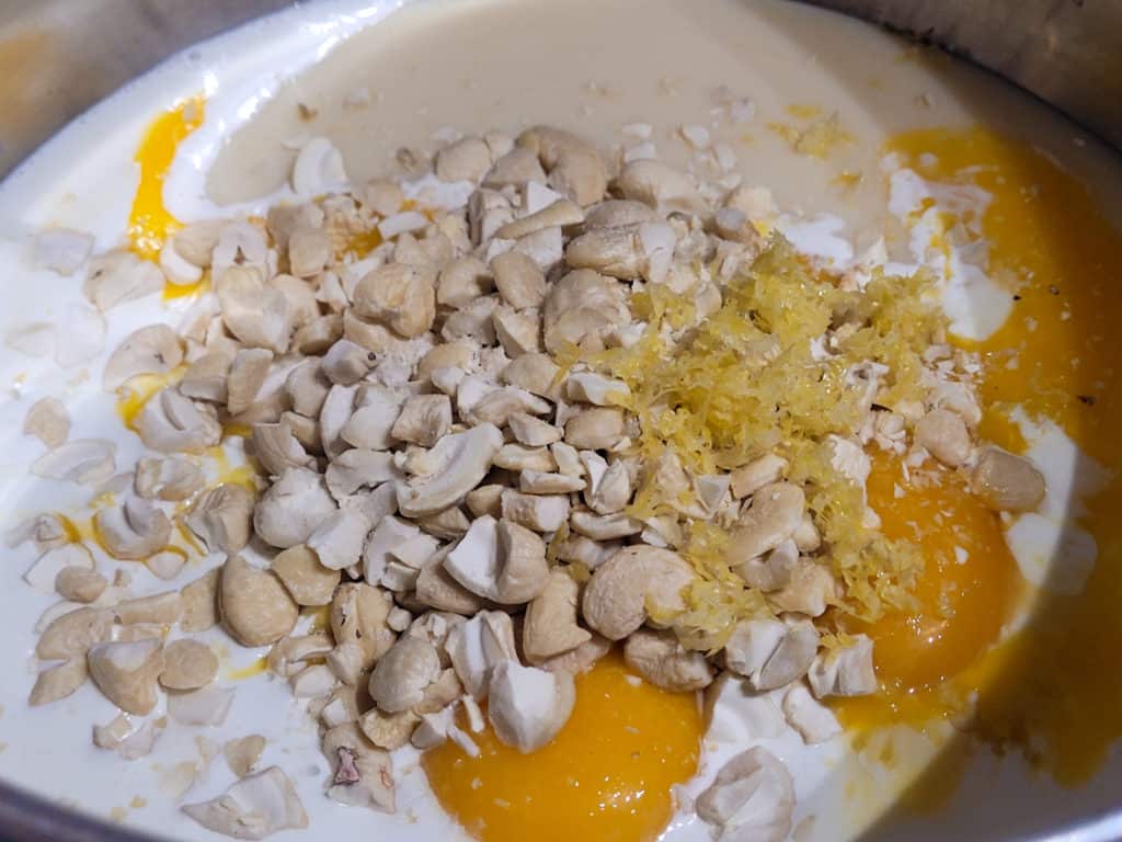 A pot filled with condensed milk, nuts, milk and egg yolks