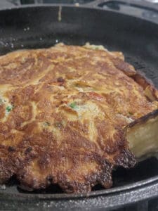 Cooked eggplant omelet with vegetables in a cast iron pan