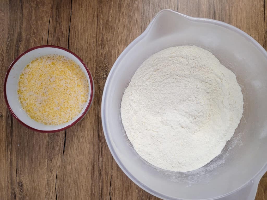 Bowl of butter and milk next to a bigger bowl of flour