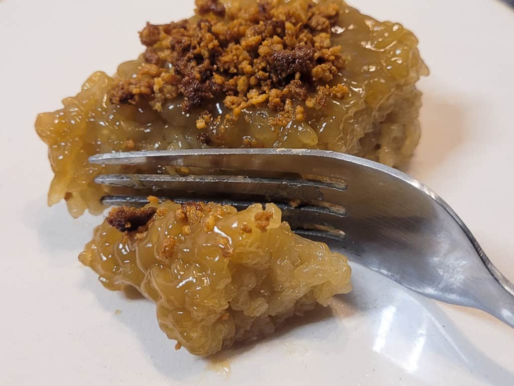 Fork and biko, a Filipino rice dessert, on a white plate