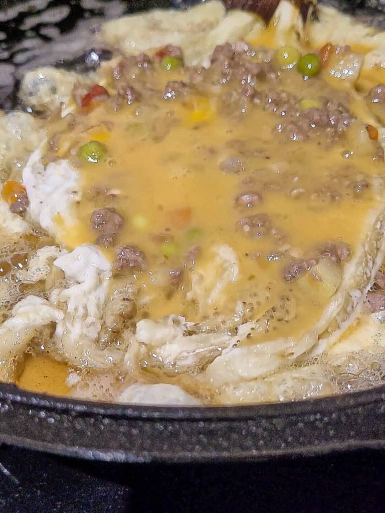 A closeup of eggplant fried with egg on a cast iron