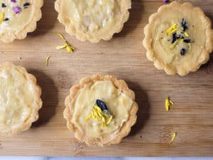 Closeup on cashew yema tarts with blue and yellow flower petals