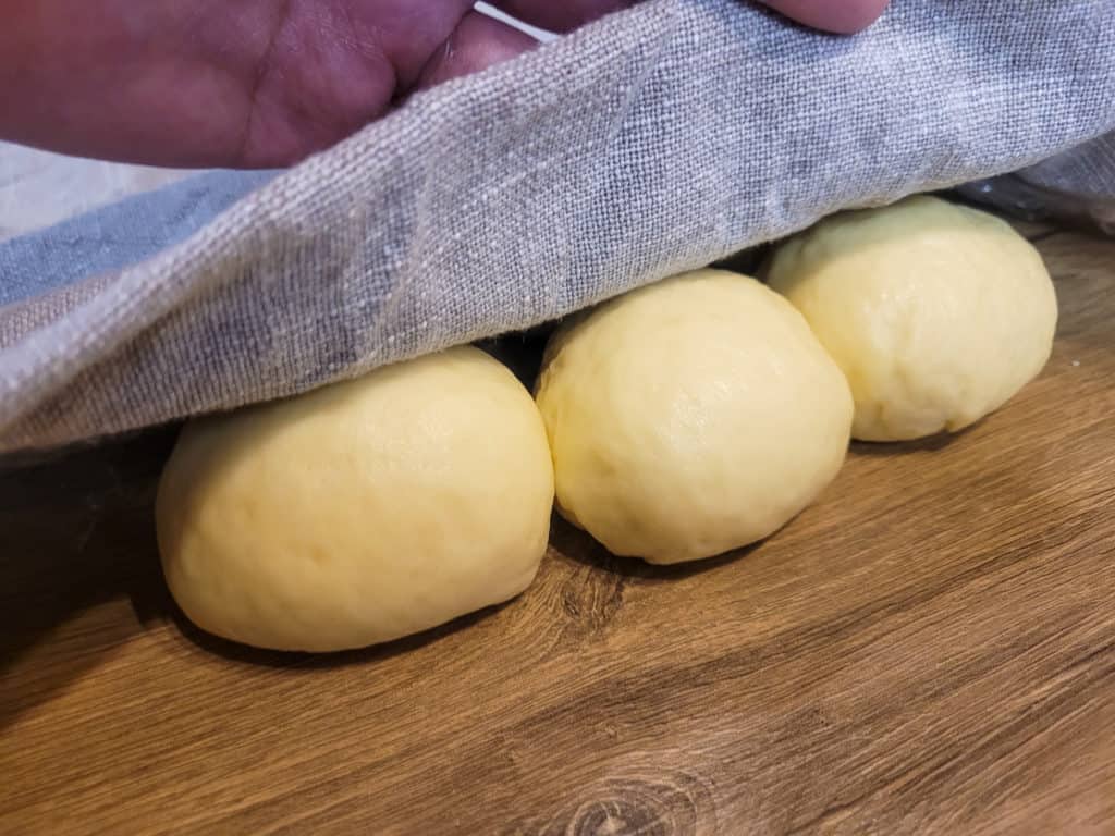 Bread rolls under a kitchen towel on a table