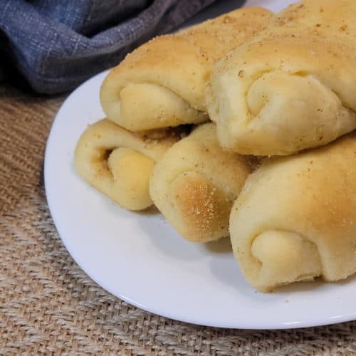 Filipino Spanish bread rolls stacked a white plate next to a blue towel