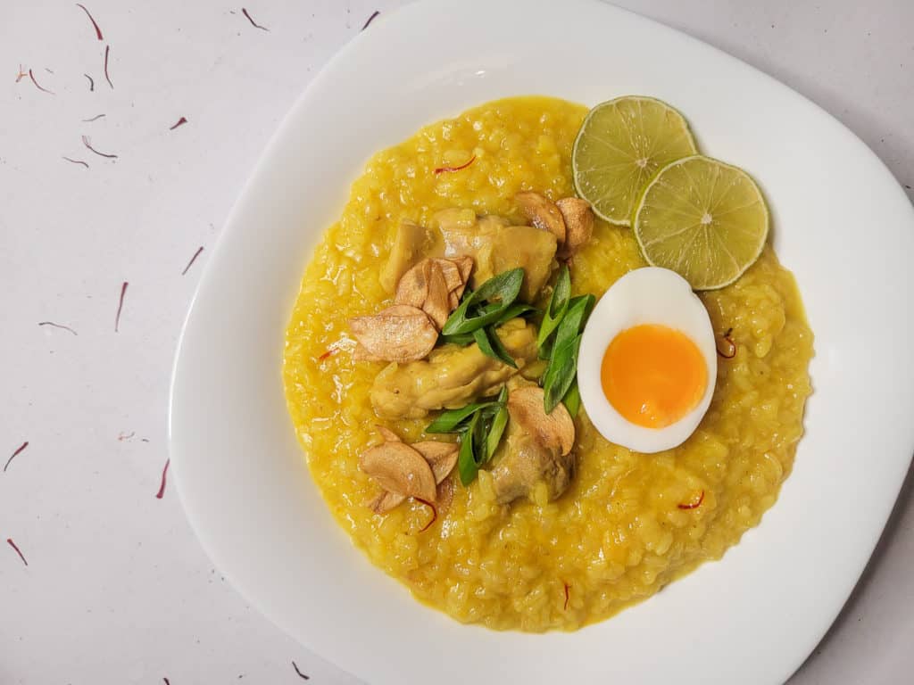Arroz caldo offset on a white tabletop with scattered saffron