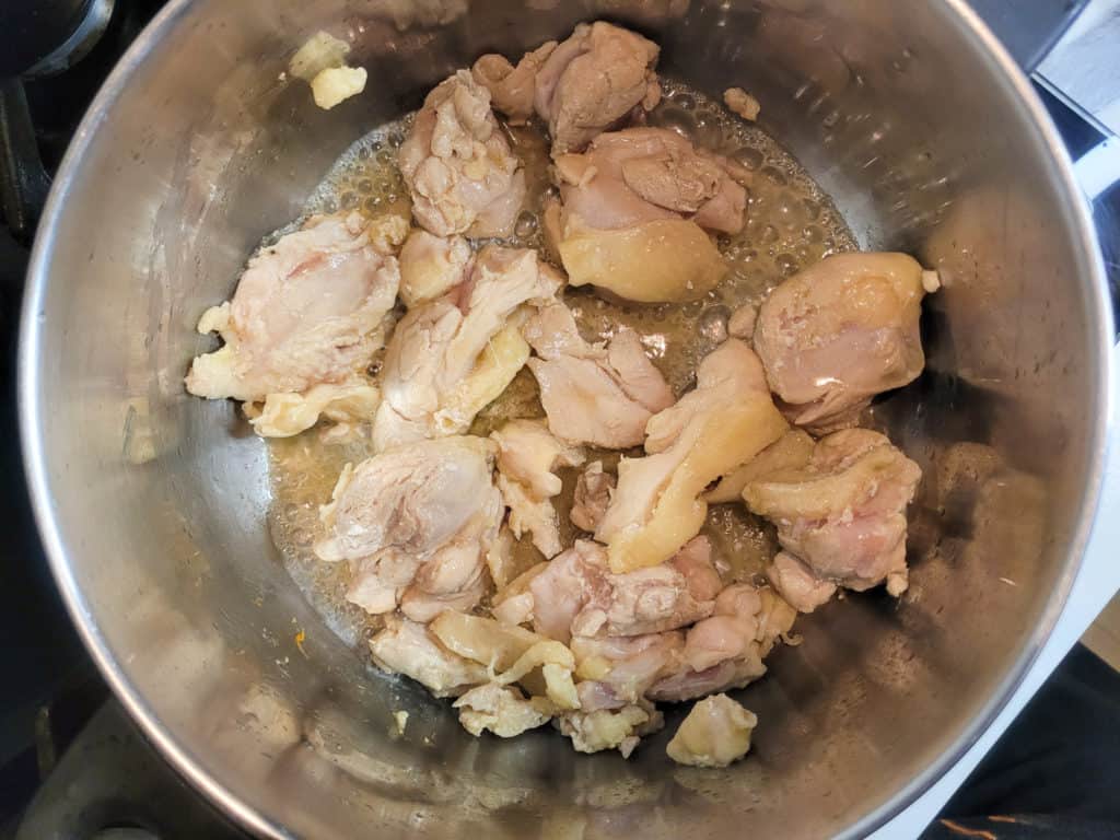 A pot with chicken thighs in the process of cooking