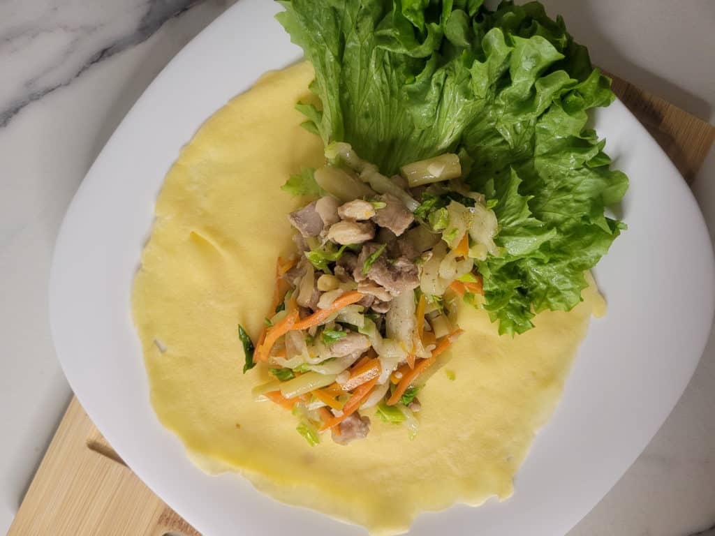 Overhead shot of crepe wrapper with lumpiang sariwa or fresh lumpia filling and lettuce