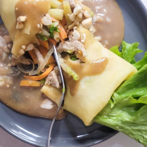 Lumpiang sariwa on a gray plate split in half with a fork