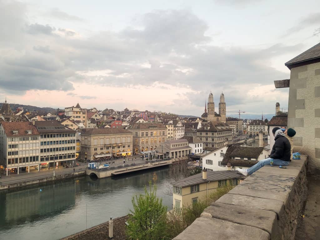 Two men sitting and drinking beer on a ledge at Lindenhof during sunset