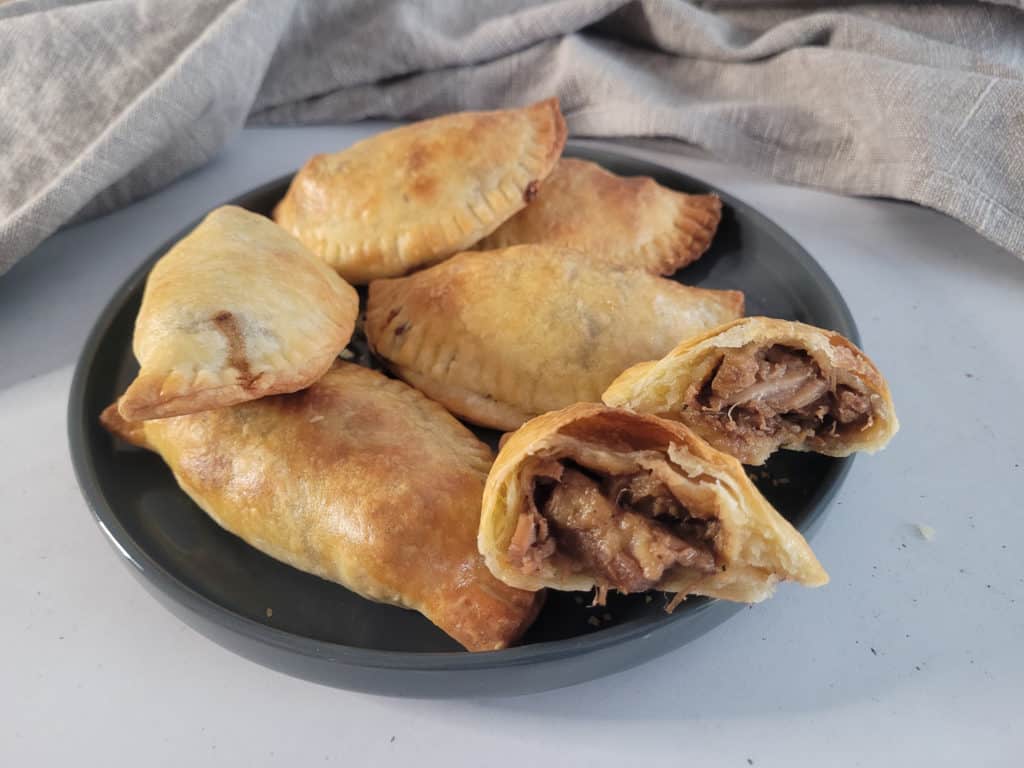 Cross section of Filipino empanada on a gray plate with other empanadas