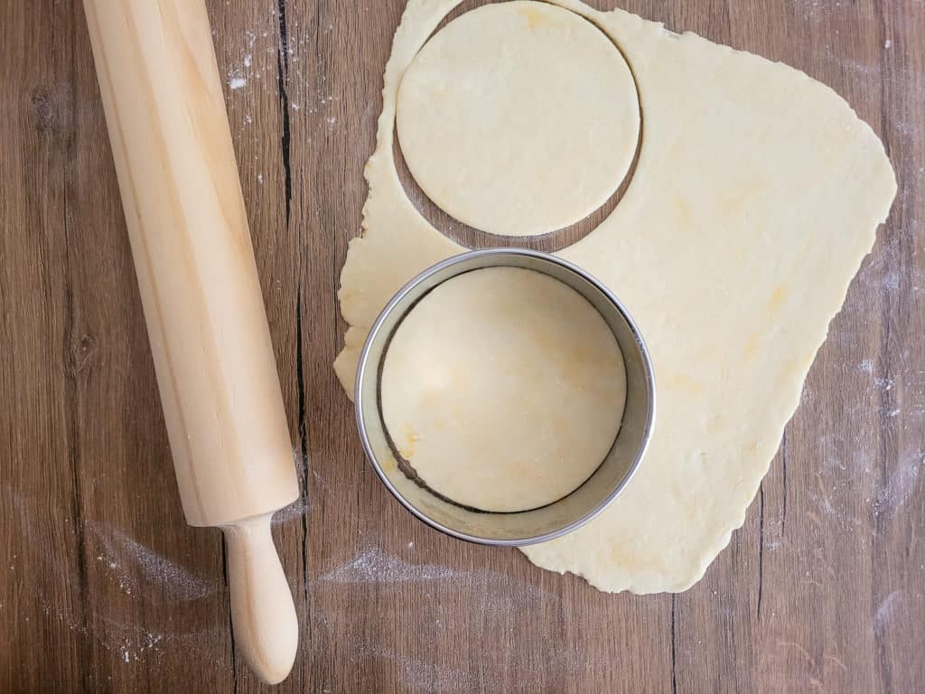 Dough cutter with pastry next to rolling pin