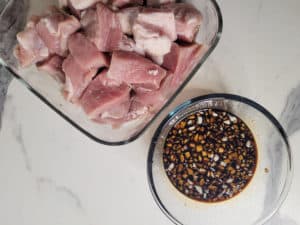 Sliced pork next to a bowl of marinade