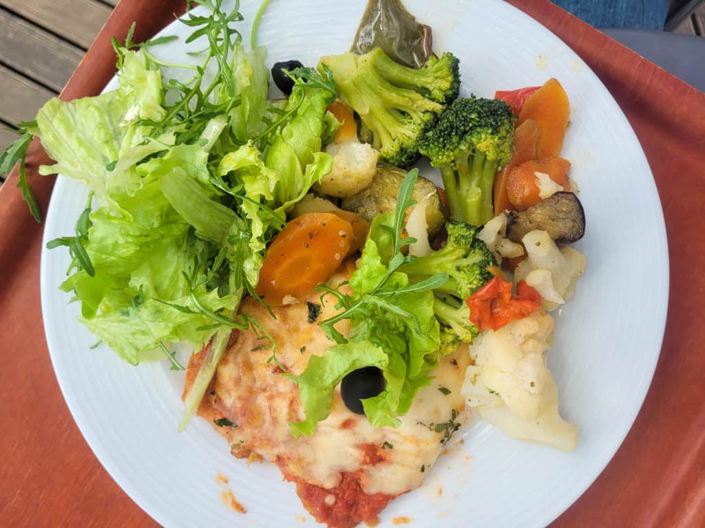 A place of chicken parmigiana with salad and vegetables on a tray