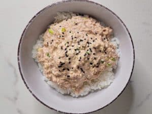 A spicy tuna mix on top of white rice in a white bowl