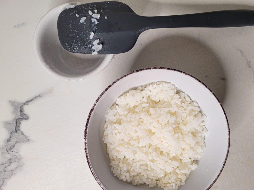 White rice in a bowl next to a used spatula