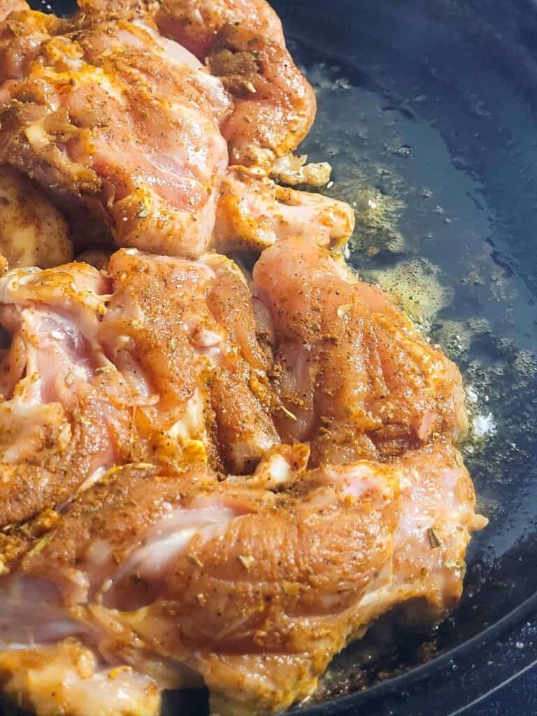 Close up of upside chicken frying in a pan