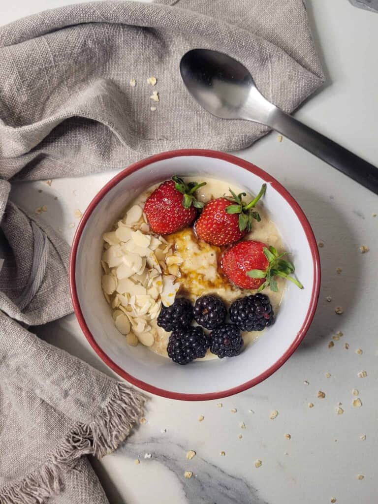 Custard oatmeal with strawberries, blackberries, and slivered almonds next to a towel