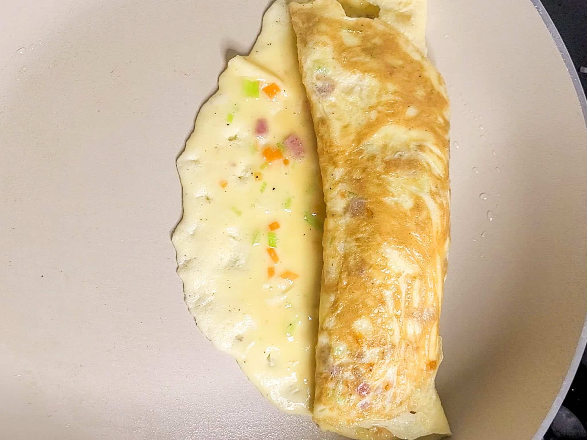 Egg omelet halfway rolled in a pan