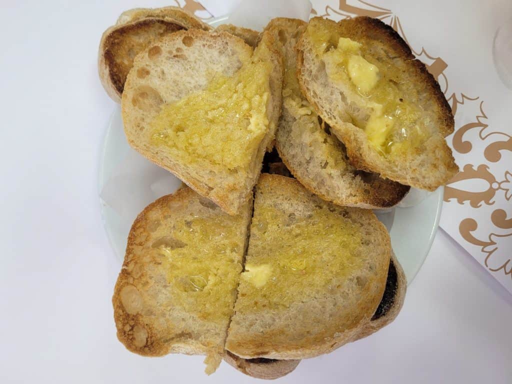 A pile of bread with butter on a small plate