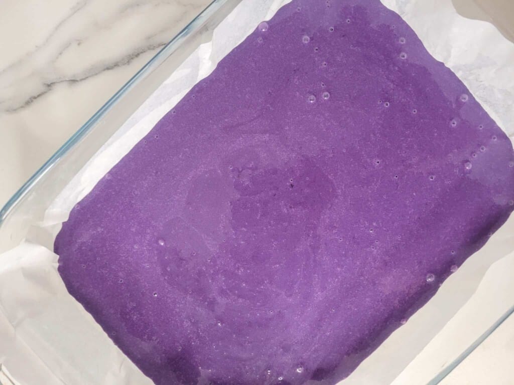 Mixed ube crunch cake batter in a lined baking dish