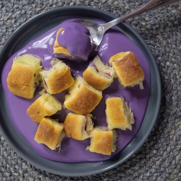 A gray plate with ube mini buns and ube cream sauce