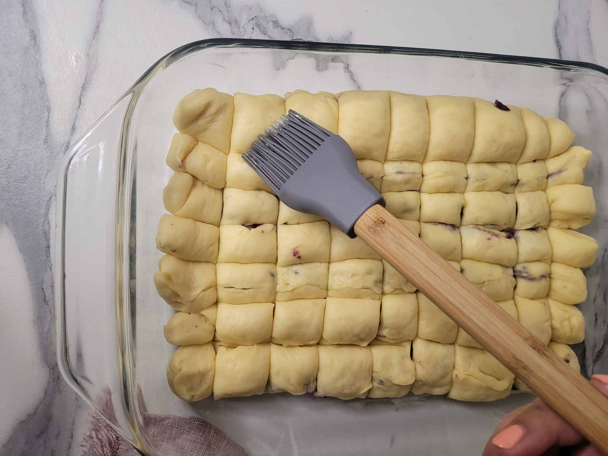 Silicone brush with leavened bread dough in a glass baking dish