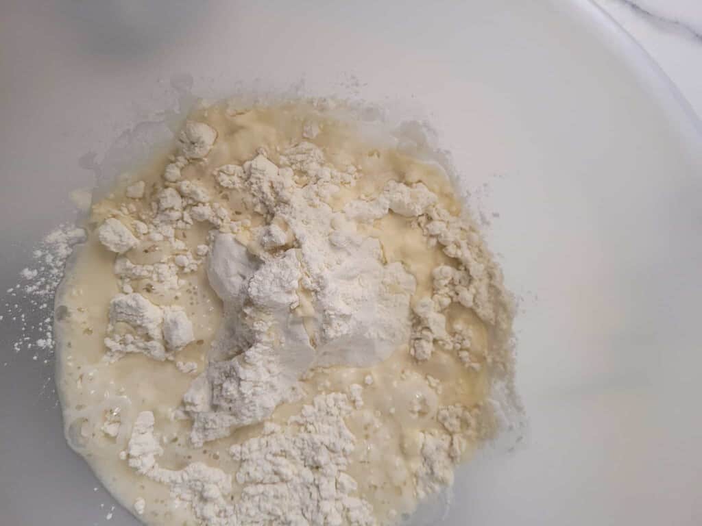 A closeup of water and flour in a plastic bowl