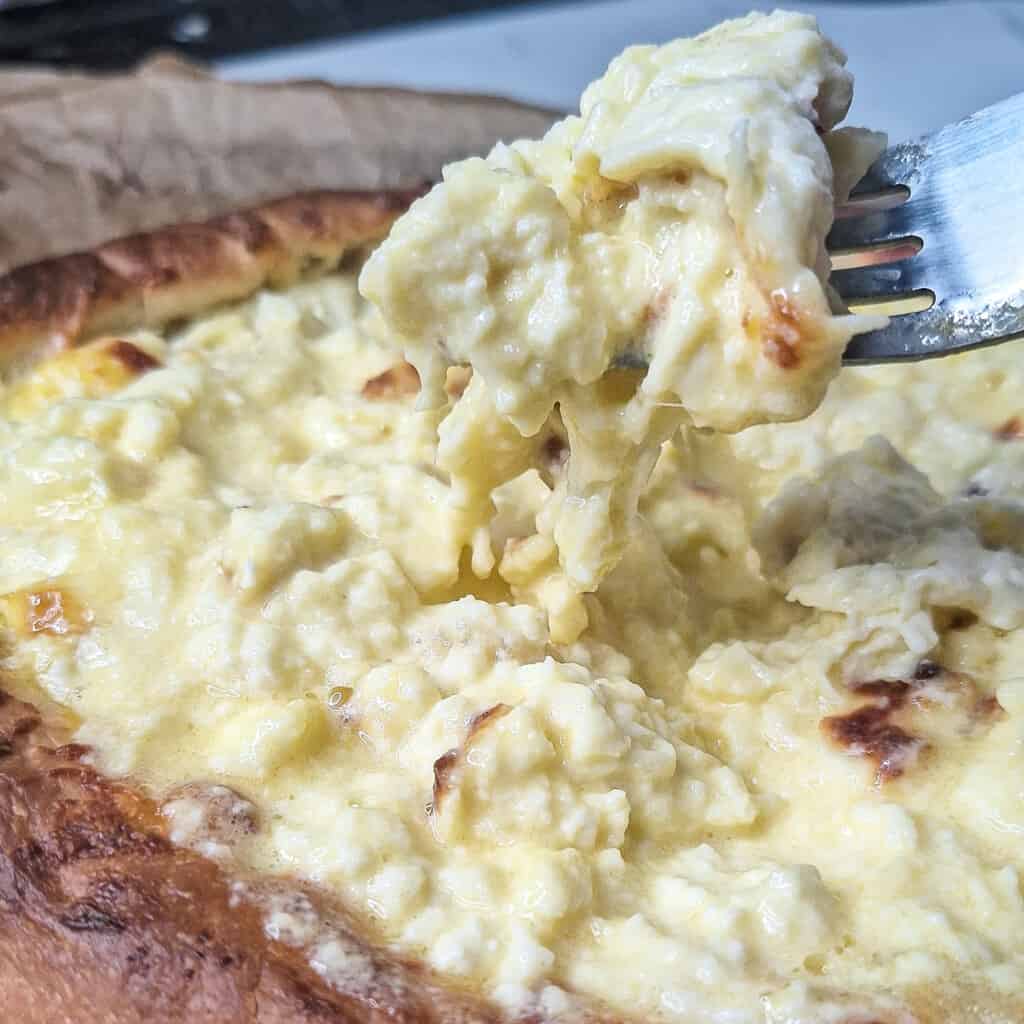 Fork holding up a cheese pull from Georgian cheese boat bread or khachapuri