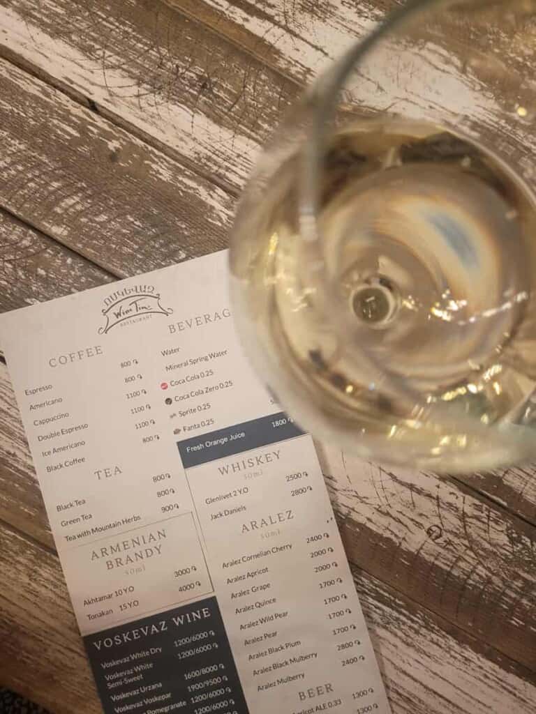 A glass of white wine on top of a menu