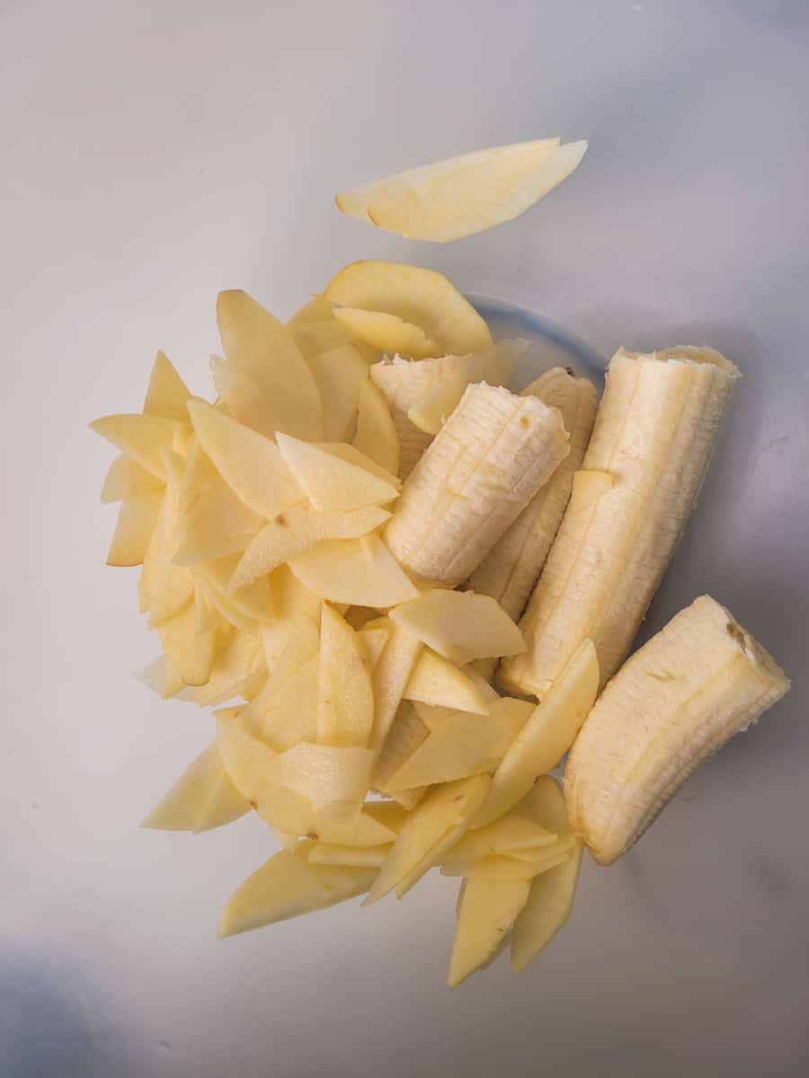 Bananas and sliced apples in a plastic bowl