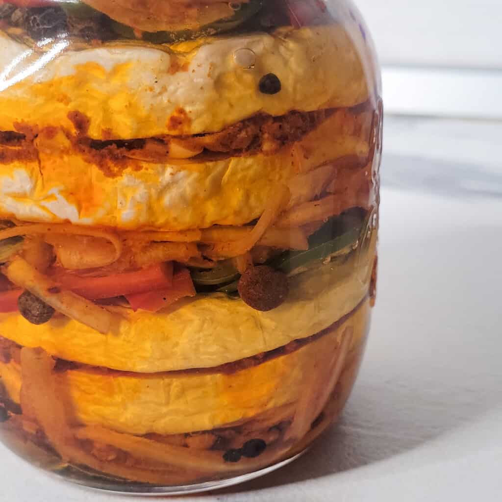 Jar filled with oil and cheese and pickling spices