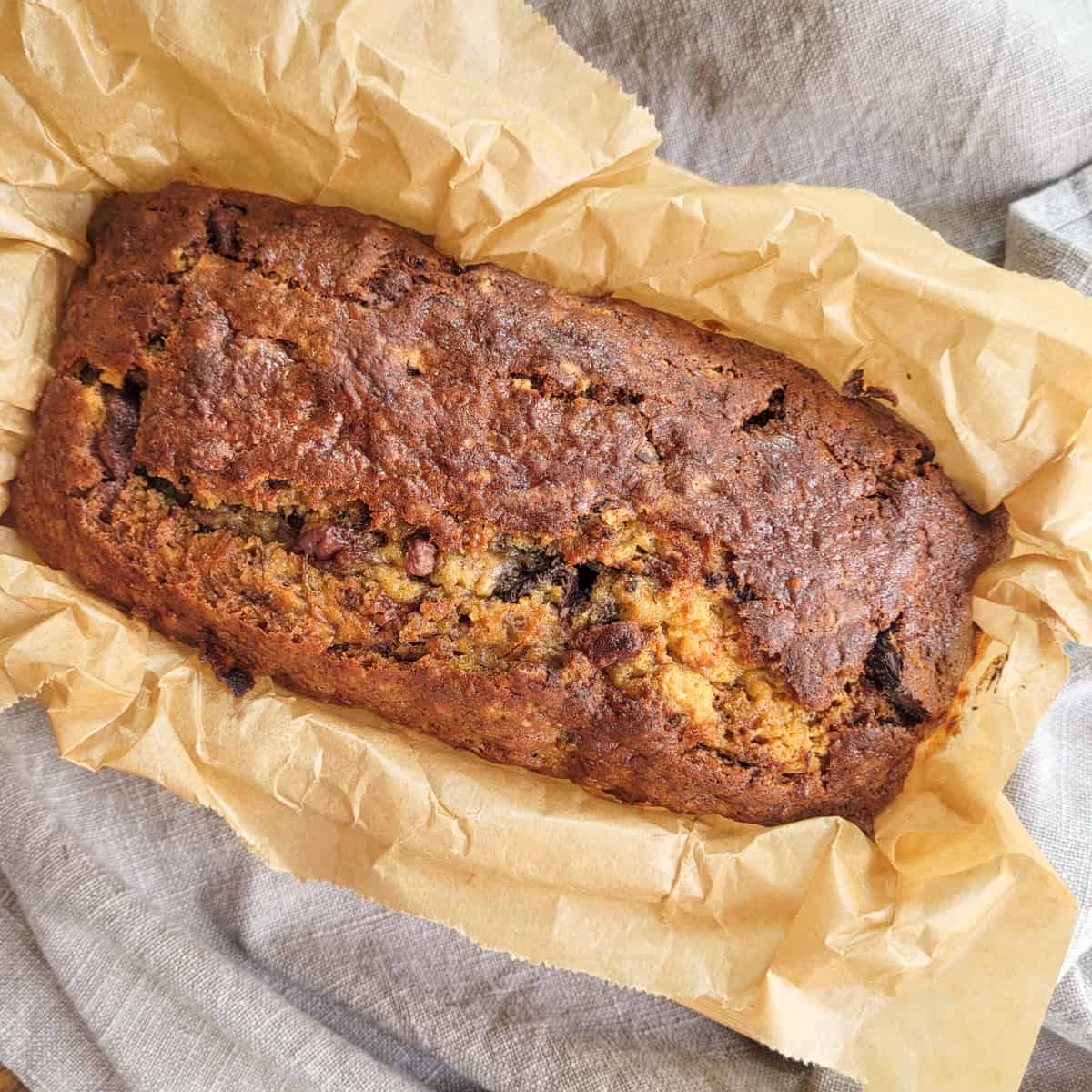 Banana bread in wax paper on top of gray towel