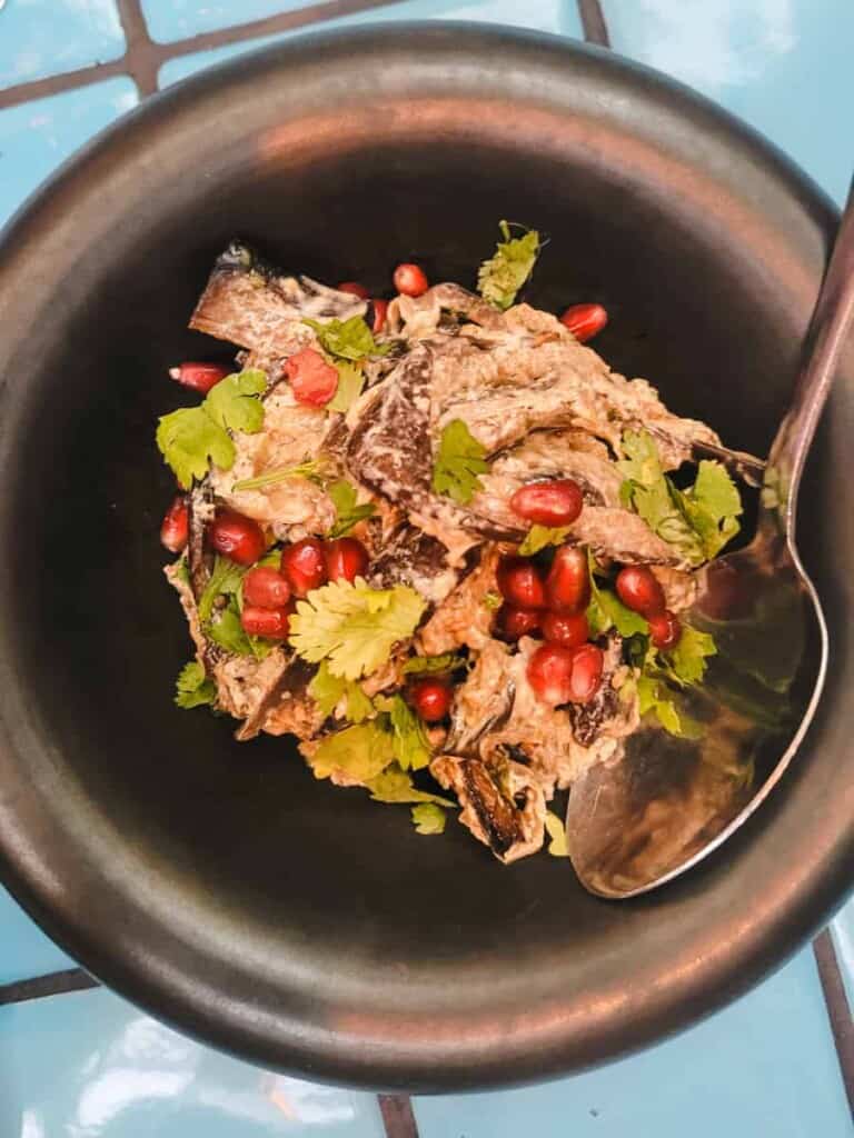 Ripped eggplant salad with pomegranates in a black bowl