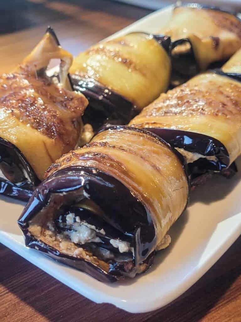 Rolled eggplants with walnut paste on a white plate